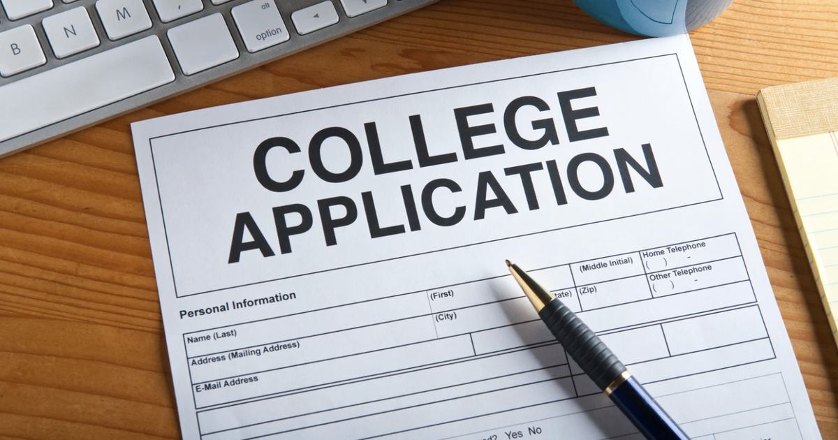 College applicant writing a Common App essay draft near a laptop